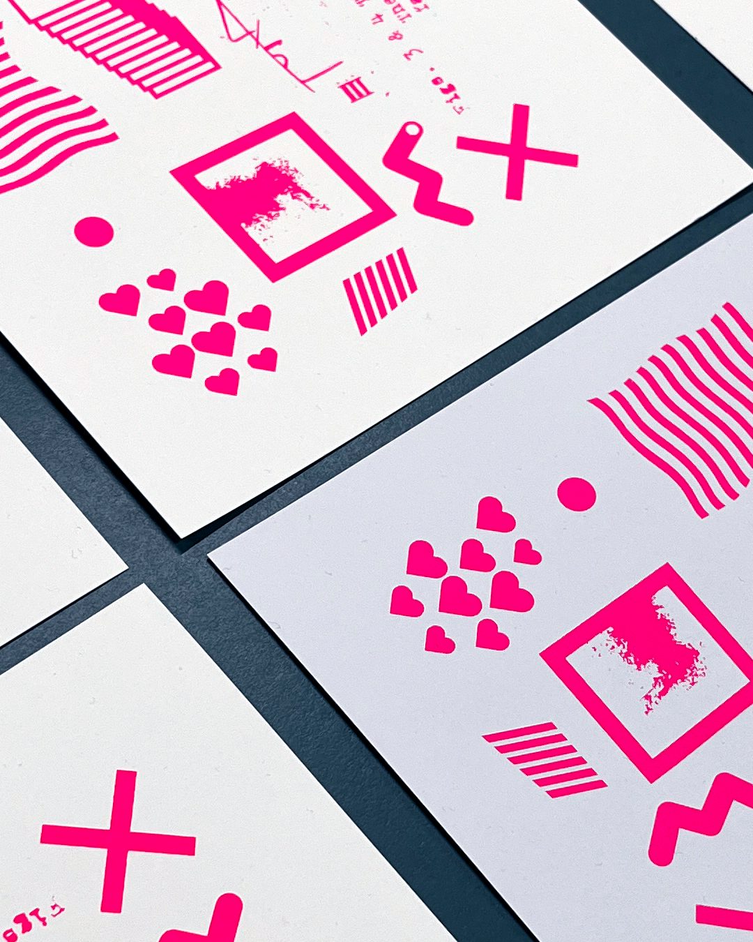 Pink screen prints of hearts, waves and geometric marks on card